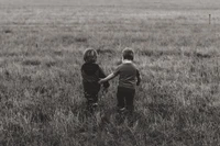 Descarga nuestro conmovedor fondo en blanco y negro de niños en un campo