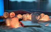 Download Cozy Still Life Wallpaper featuring a Teacup and Fairy Lights