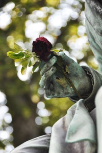 Impresionante escultura con una mano y una rosa