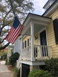 Hermoso Wallpaper de una Casa Amarilla con Bandera Americana