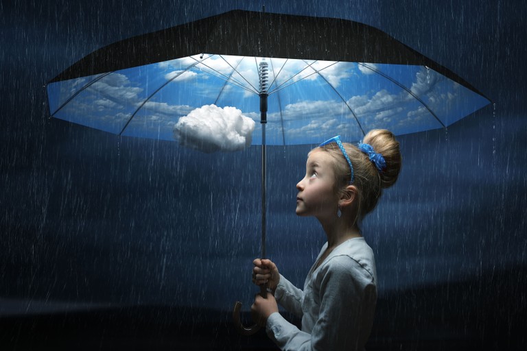 Enchanting Child with Umbrella Under a Blue Cloudy Sky